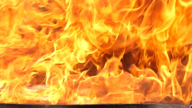 Slow motion speed close up scene of moving burning pattern as background. hot as inferno flame concept, abstract beautiful fire texture with flakes of spark, black smoke from petroleum oil ignition