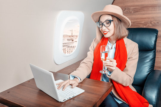 Asian businesswoman flies in business class and works with a laptop and smartphone in Paris, France. Concept of a successful lifestyle and transportation