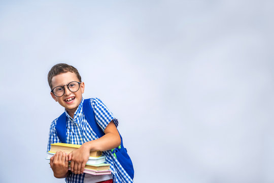 Back to school. Funny boy with glasses, laughing merrily on gray background.