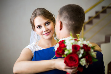groom in a blue suit and the bride in a Wedding dress the newlyweds, embracing, pose together on the stairs
