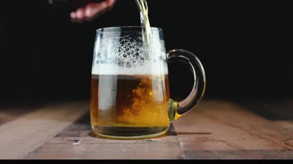 Pouring beer into large glass mug closeup