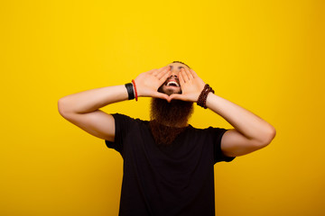Excited young  man shouting with hands cupped around mouth isolated on yellow background.  Smiling emotional man screaming on yellow studio background. Human emotions, facial expression concept. 
