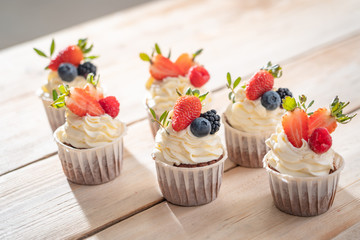 Fresh, delicious cupcakes with yogurt cream and fresh berries. Blur background.