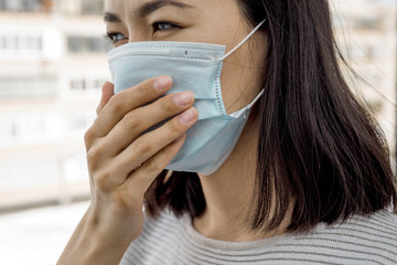 portrait of a young Asian woman in a medical mask close - up on the street. protection from...