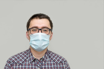 portrait of a young man in a medical mask on a gray background close-up copy . protection from the virus pandemic