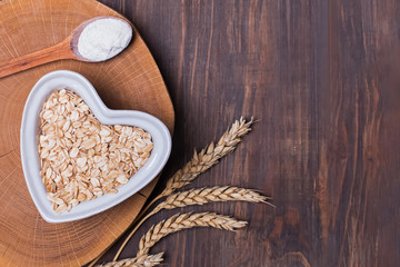 Oats, wheat ears and flour in the spoon on the wooden table