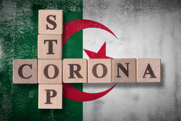 Obraz premium Flag of Algeria with wooden cubes spelling STOP CORONA on it. 2019 - 2020 Novel Coronavirus (2019-nCoV) concept art, for an outbreak occurs in Algeria.
