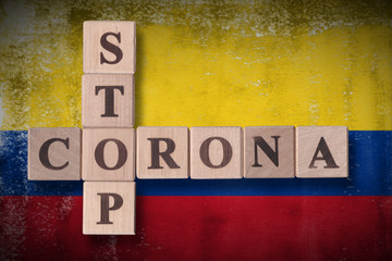 Obraz premium Flag of Colombia with wooden cubes spelling STOP CORONA on it. 2019 - 2020 Novel Coronavirus (2019-nCoV) concept art, for an outbreak occurs in Colombia.