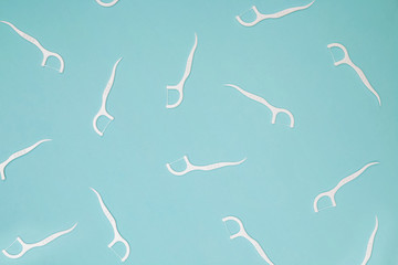 Many dental floss picks on blue color background, top view.