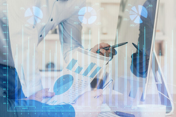 Double exposure of chart with businessman typing on computer in office on background. Concept of...