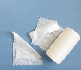 Disposable synthetic non- woven cleaning cloths in a roll, on a blue background. Cosmetic towels Spunlace. The concept of personal hygiene.