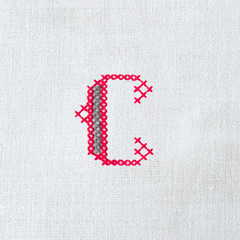 Vintage cross-stitch letter C on linen fabric