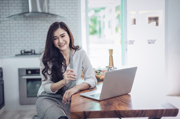 Portrait of beautiful young latin woman talking over the phone while cooking in kitchen