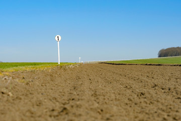 Low down, shallow focus of a 1 furlong marker sign seen at the edge of a race horse flat racing...