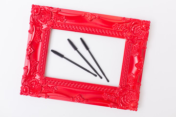Group of black makeup brushes from a top, eyelash and eyebrow combs on a white background in red art frame