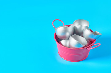 Red metal basin full of silver egg shells on blue background. Easter concept. Copy space