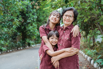 togetherness of grandma with two granddaughter having fun and playing in the park