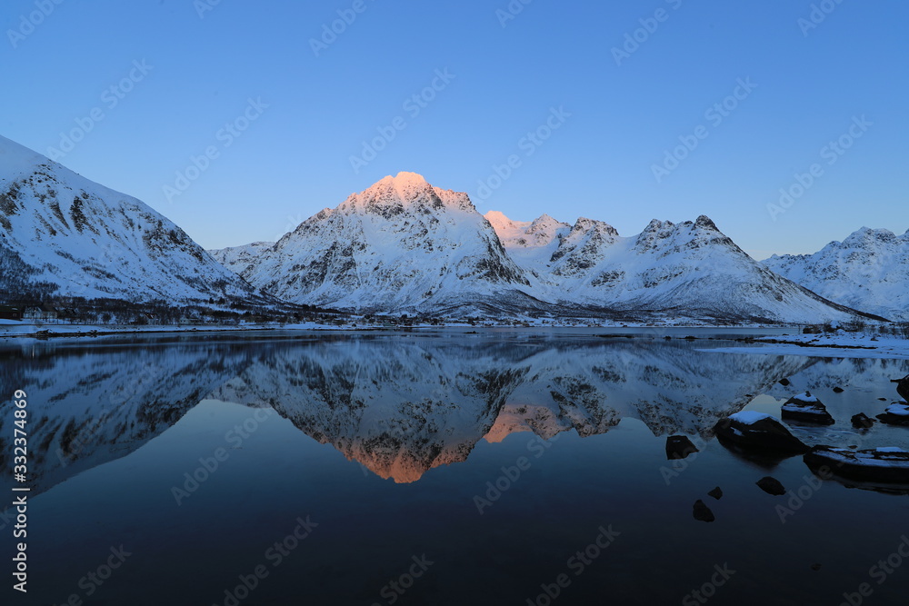 Wall mural snow mountain refelcted in lake Norway