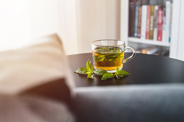 Mint tea on black table. Library in background. Tea time. Yellow tea close up.