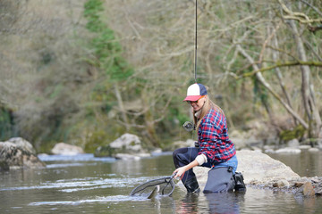 woman catching rainbow trout fly in river