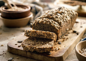 Gluten-free homemade buckwheat bread with the addition of various seeds cut into slices on a wooden board close up
