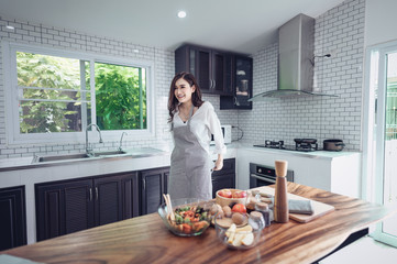 Portrait of beautiful young latin woman talking over the phone while cooking in kitchen