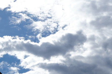 White light fluffy clouds in a blue sky with a solar flare.
