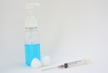 Press-type alcohol bottles, cotton buds, syringes placed on a white background