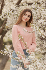 Portrait of pretty young girl in the garden of blossom cherry trees. Spring time