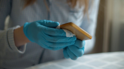 Hands cleaning smartphone with a disinfectant napkin