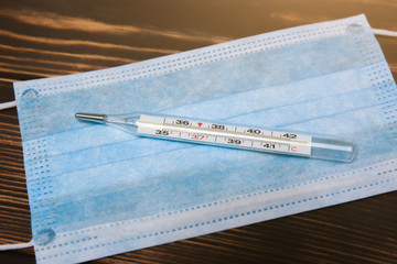 Medical mask and mercury thermometer. Virus illness. Coronavirus pandemia danger. Flu and cold in...