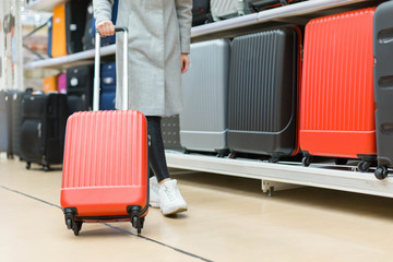 Woman buying a new big colorful  hardside suitcase in a store. Many travel suitcase on backgroung 