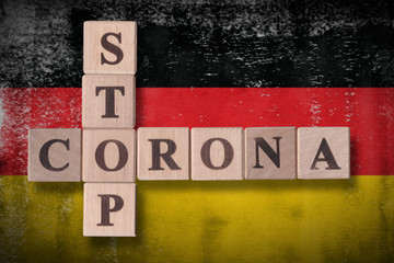 Fototapeta premium Flag of Germany with wooden cubes spelling STOP CORONA on it. 2019 - 2020 Novel Coronavirus (2019-nCoV) concept art, for an outbreak occurs in Germany.