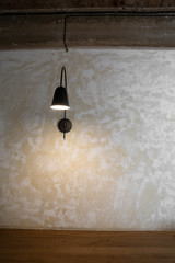Stylish industrail wall sconce in black metal install on concrete wall with natural wood table top  / copy space / background concept