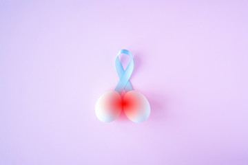 prostate cancer, healthcare, profession, medicine concept - close up of chicken white eggs and blue ribbon with hurt red signs on bright background. Cancer awareness, cure, men carcinoma