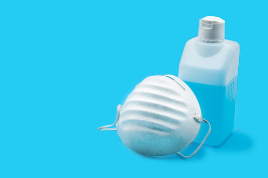 Disinfectant and face mask on blue background. Copy space