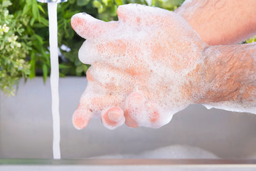 Male hands being washed at a sink outdoors