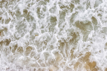 Fototapeta na wymiar Top view texture waves, foaming and splashing in the ocean, sunny day. Beautiful tropical sea in summer season image by aerial view. Abstract sea background. Ocean waves close-up.