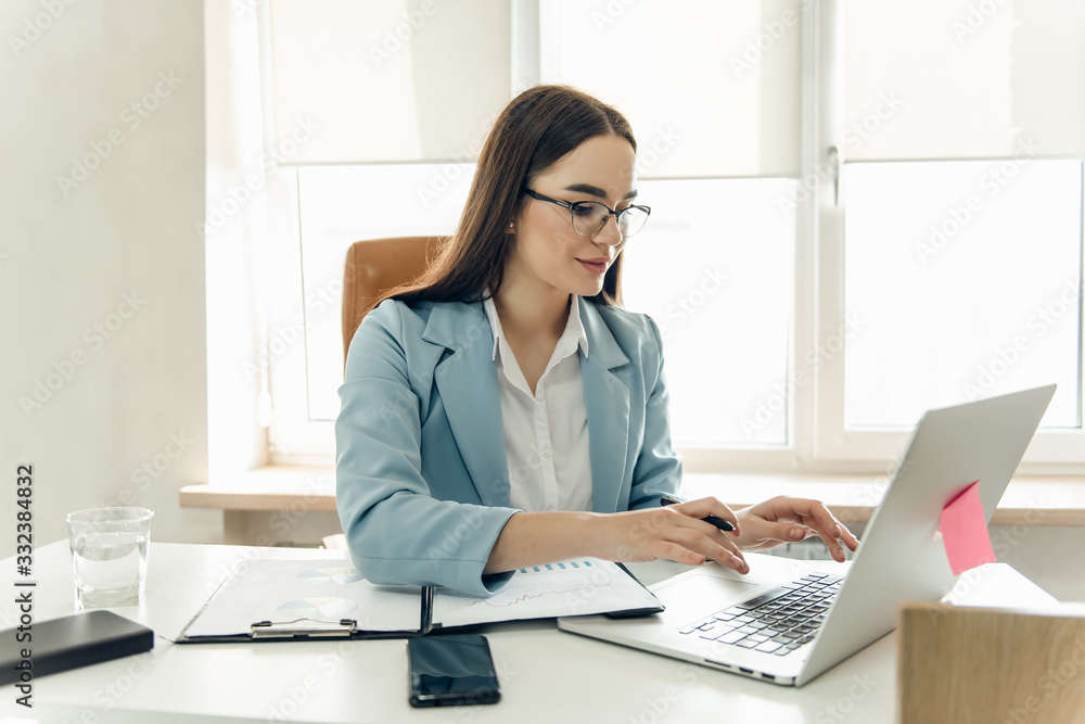 Wall mural young focused woman working with chart. young beautiful businesswoman in glasses working.