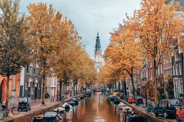 Autumn on a canal in Amsterdam with clock tower in background.