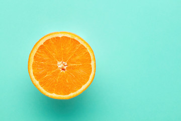 One slice of orange on blue background with copy space