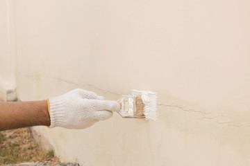 Close up of a hand with white cloth gloves that is being used to transform paint to seal the cracks...