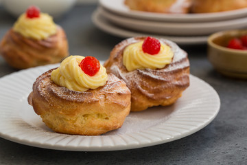 Italian pastry - zeppole di San Giuseppe - baked cream puffs made from choux pastry, filled and decorated with custard cream and cherry. It is eaten to celebrate Saint Joseph's Day.