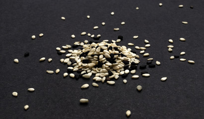 Black and white sesame seeds on black background, macro, close up