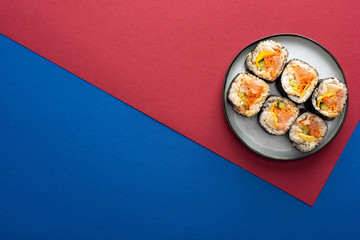 top view of plate with gimbap on crimson and blue