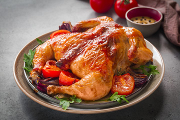 Roasted  chicken with garlic, spices and vegetables: tomatoes and red onions. 