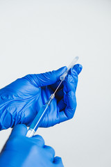 Doctor or nurse holding medical injection syringe wearing surgical rubber gloves. Coronavirus antidote biohazard