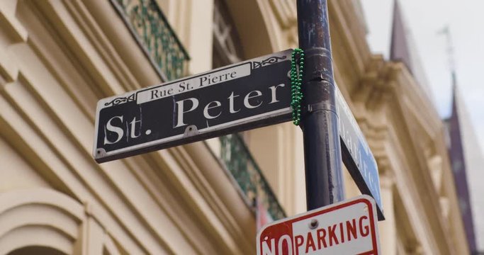 New Orleans St. Peter Street sign with NOLA Decor in the background as they move in slow motion.
