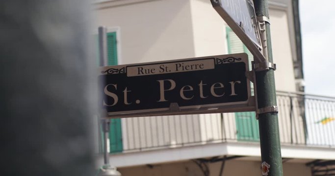 New Orleans St. Peter Street sign with NOLA Decor and buildings in the background as they move in slow motion.