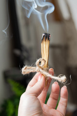Naturalna aromaterapia w domu. Kobieca ręka trzyma dymiące się drewienko, kadzidło.  - obrazy, fototapety, plakaty